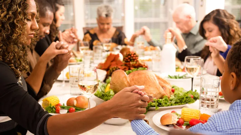 Family and friends saying a prayer before dinner