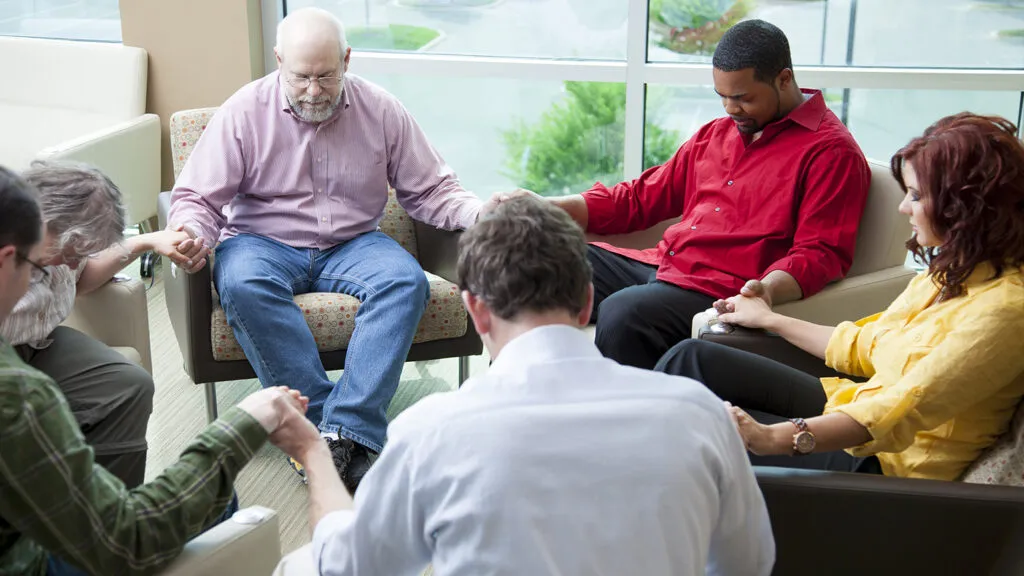 A group prays, hands clasped