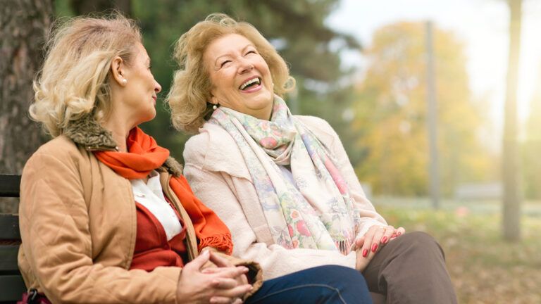 Women laughing together while sitting on a bench
