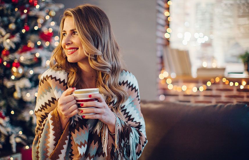 Cozy woman smiling by the Christmas tree