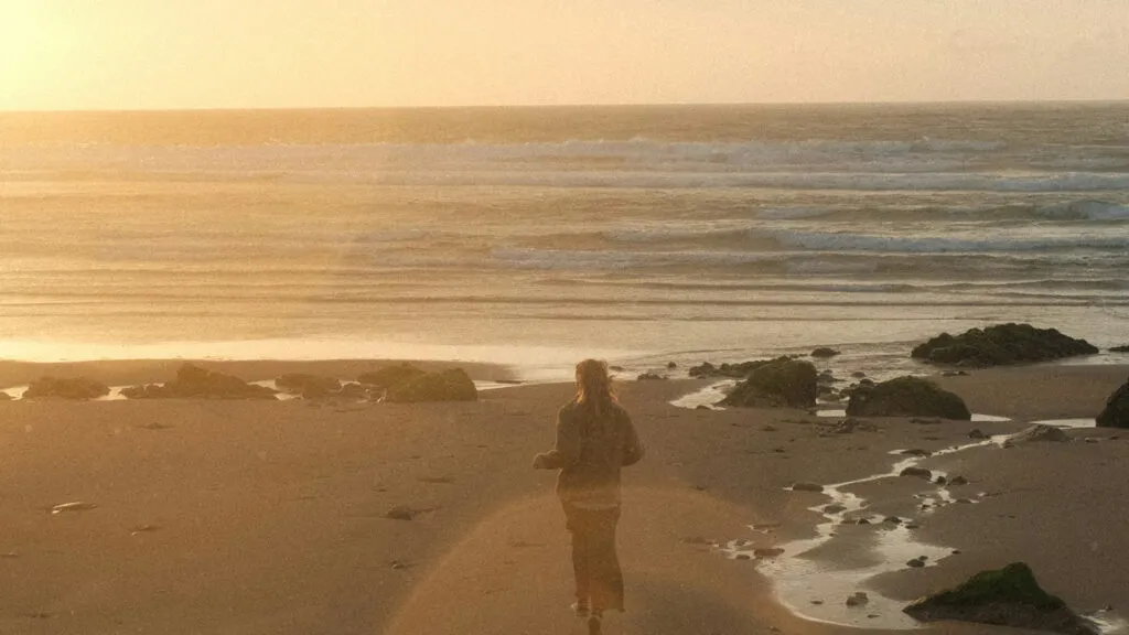 A woman standing on a beach during golden hour. Credit: Unsplash