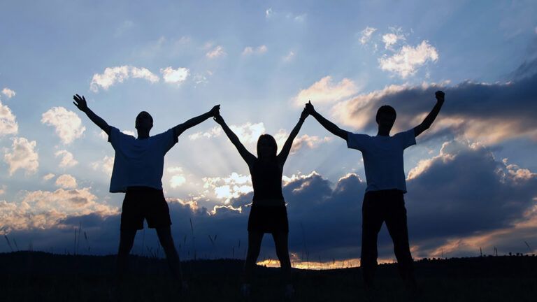 Three people holding hands up to the sky
