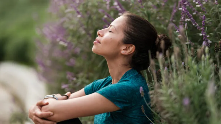 Woman sits in a garden with her eyes closed thinking about how to do lent