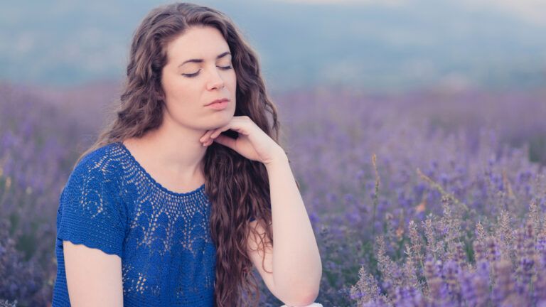 Woman with her eyes closed in a field of purple flowers to celebrate lent