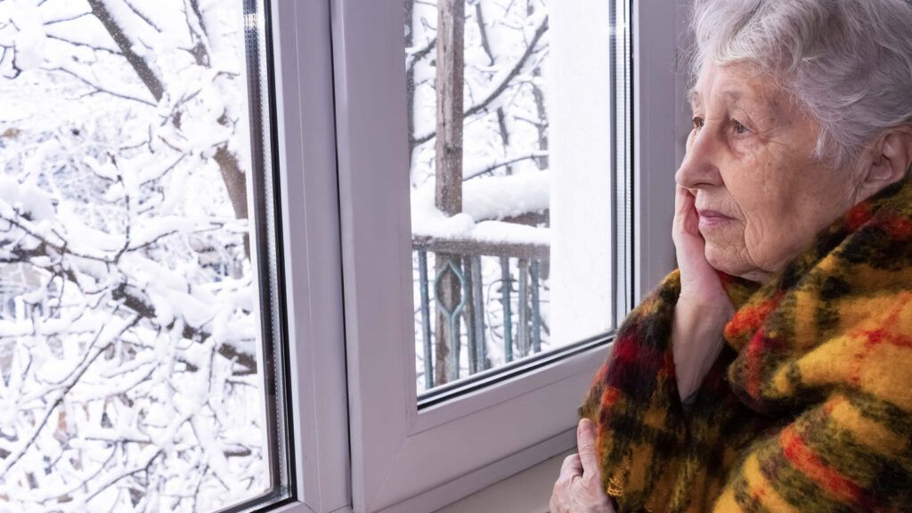 A senior woman looking out of her window; Getty Images