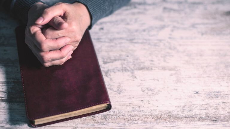 A man's hands rest on a Bible