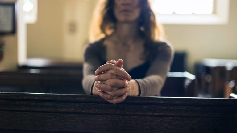 A woman prays silently alone in church