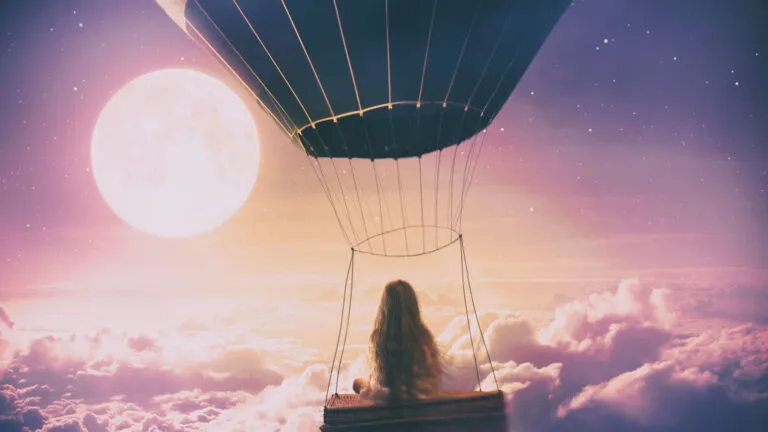 Young girl in a hot air balloon above clouds; Getty Images