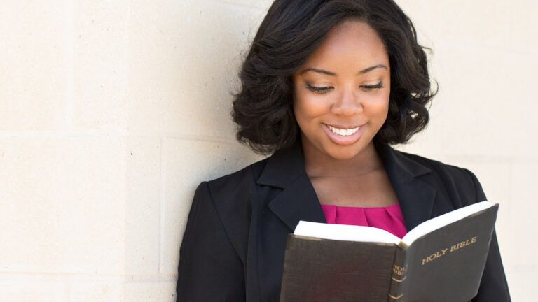 A smiling woman reads the Bible