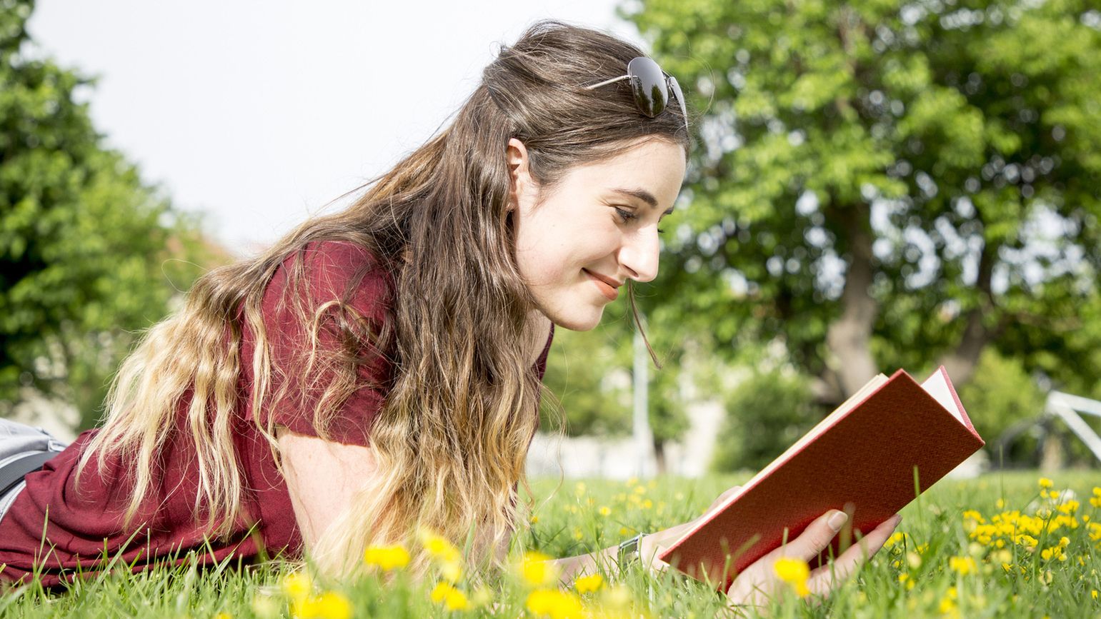 Woman reading book in field during spring (Getty Images)