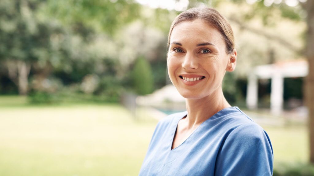 A smiling female caregiver; Getty Images
