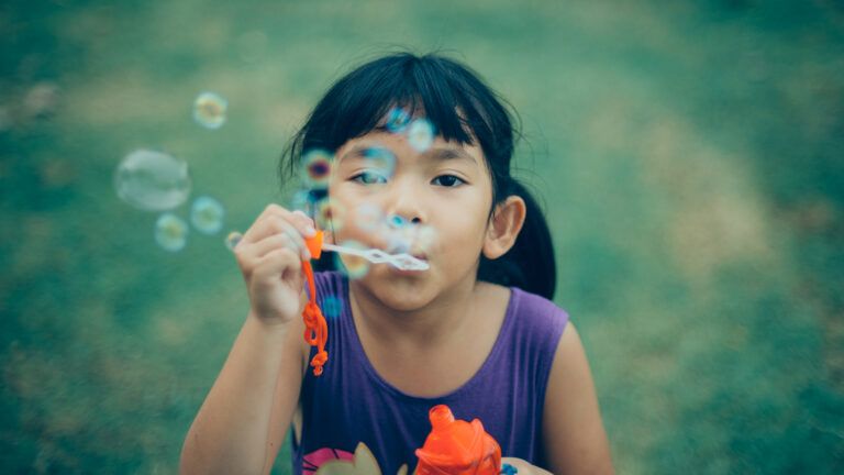 A young girl blows bubbles