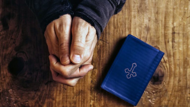 A man's hands clasped in prayer