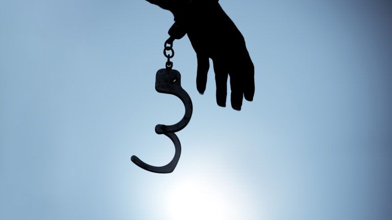 Silouette of hand with open handcuffs; Photo credit: Chanin Wardkhian/Getty Images