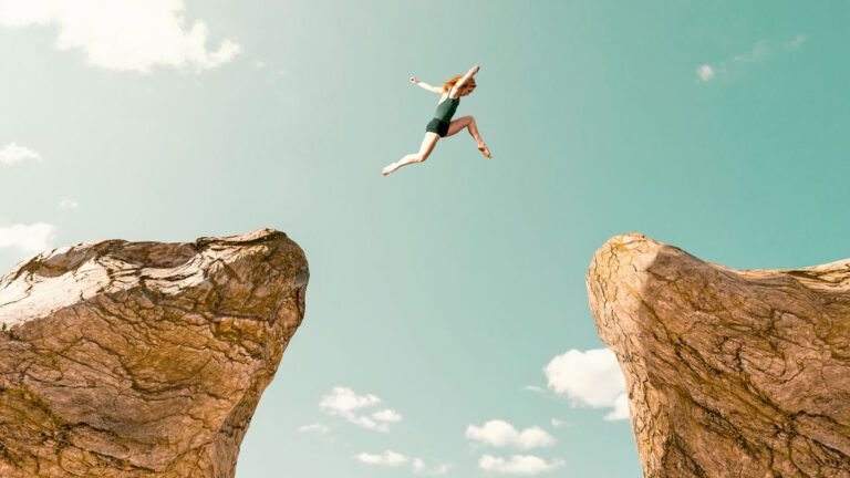 A woman leaping across a cliff; Getty Images