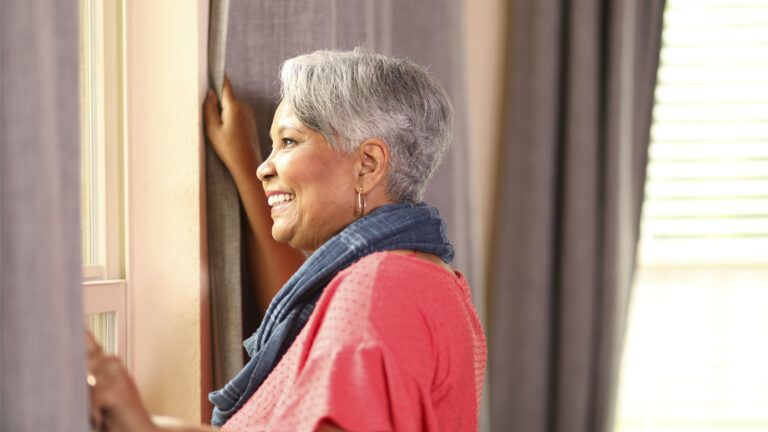 A senior woman looking out of a window; Getty Images