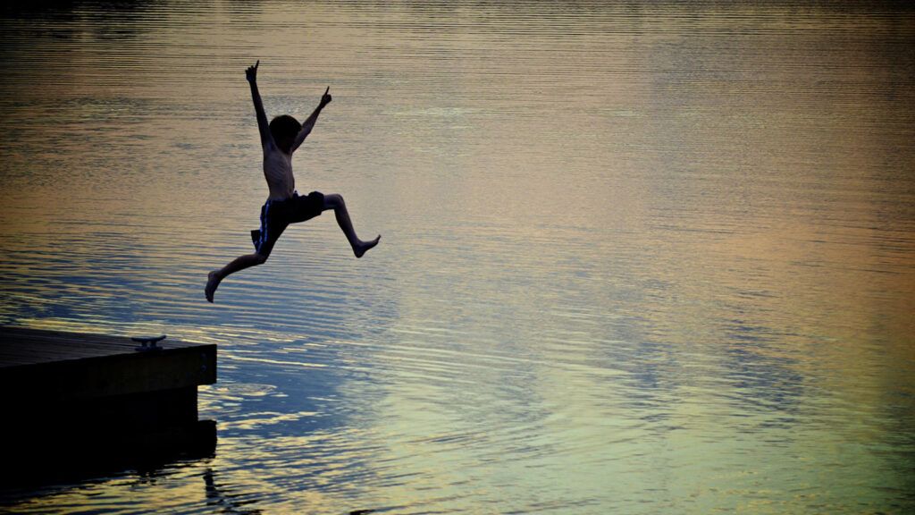 A boy leaps into a lake from a float/Melnotte/iStock/Getty Images Plus