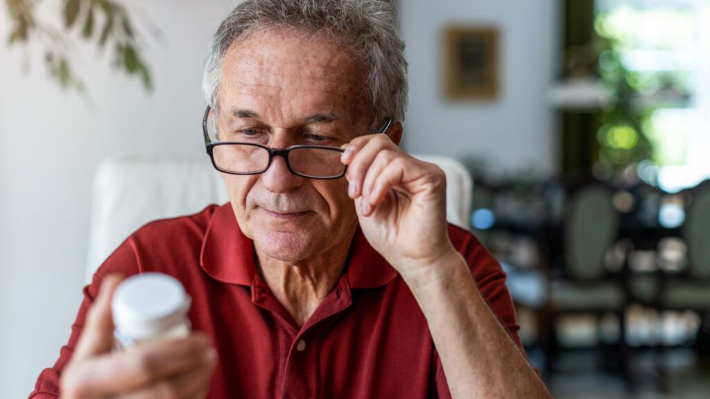 A senior man taking a look at a medication label; Getty Images