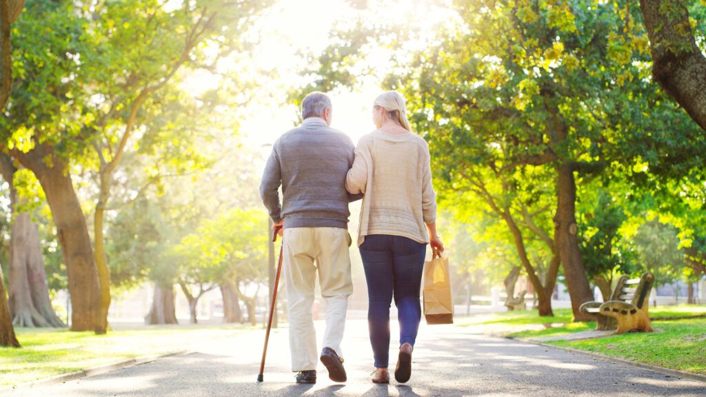 An elderly man walking with his caregiver; Getty Images