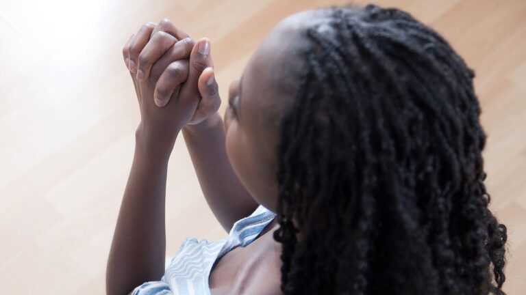 A woman clasps her hands in prayer