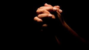 Praying hands in the dark