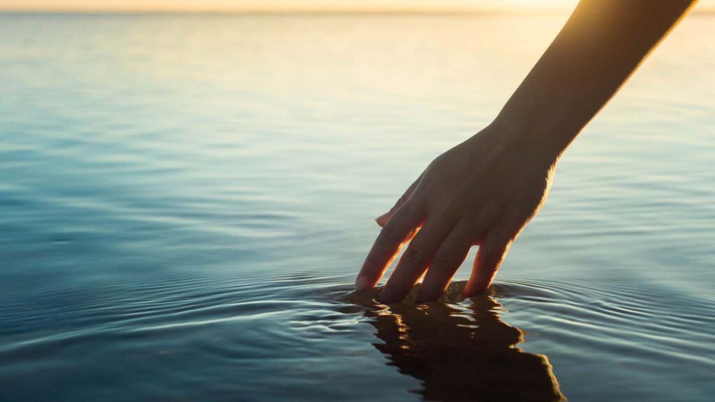 Touching ocean water during sunset; Getty Images
