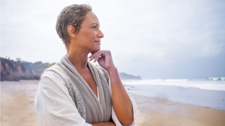 A smiling woman gazes out at the ocean