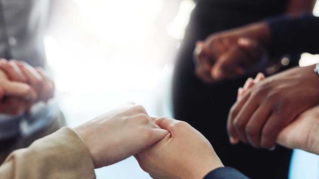Hands holding each other in a circle; GETTY IMAGES/ISTOCKPHOTO