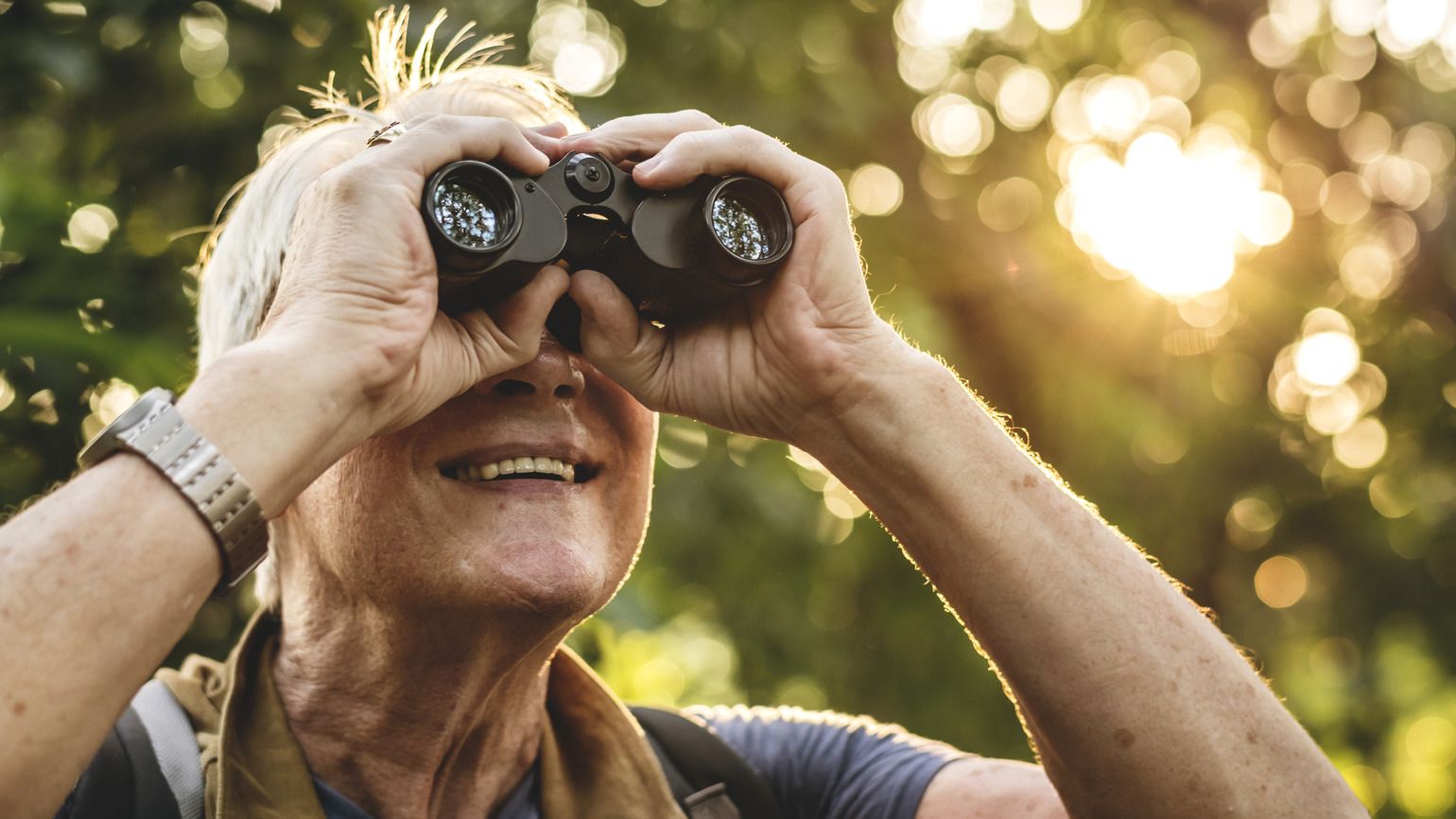 Man watching birds through binoculars (Getty Images)