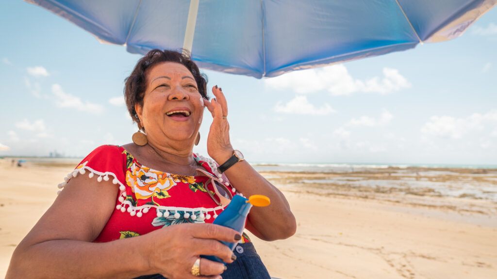 Senior woman using a suntan lotion on the beach (Getty Images)