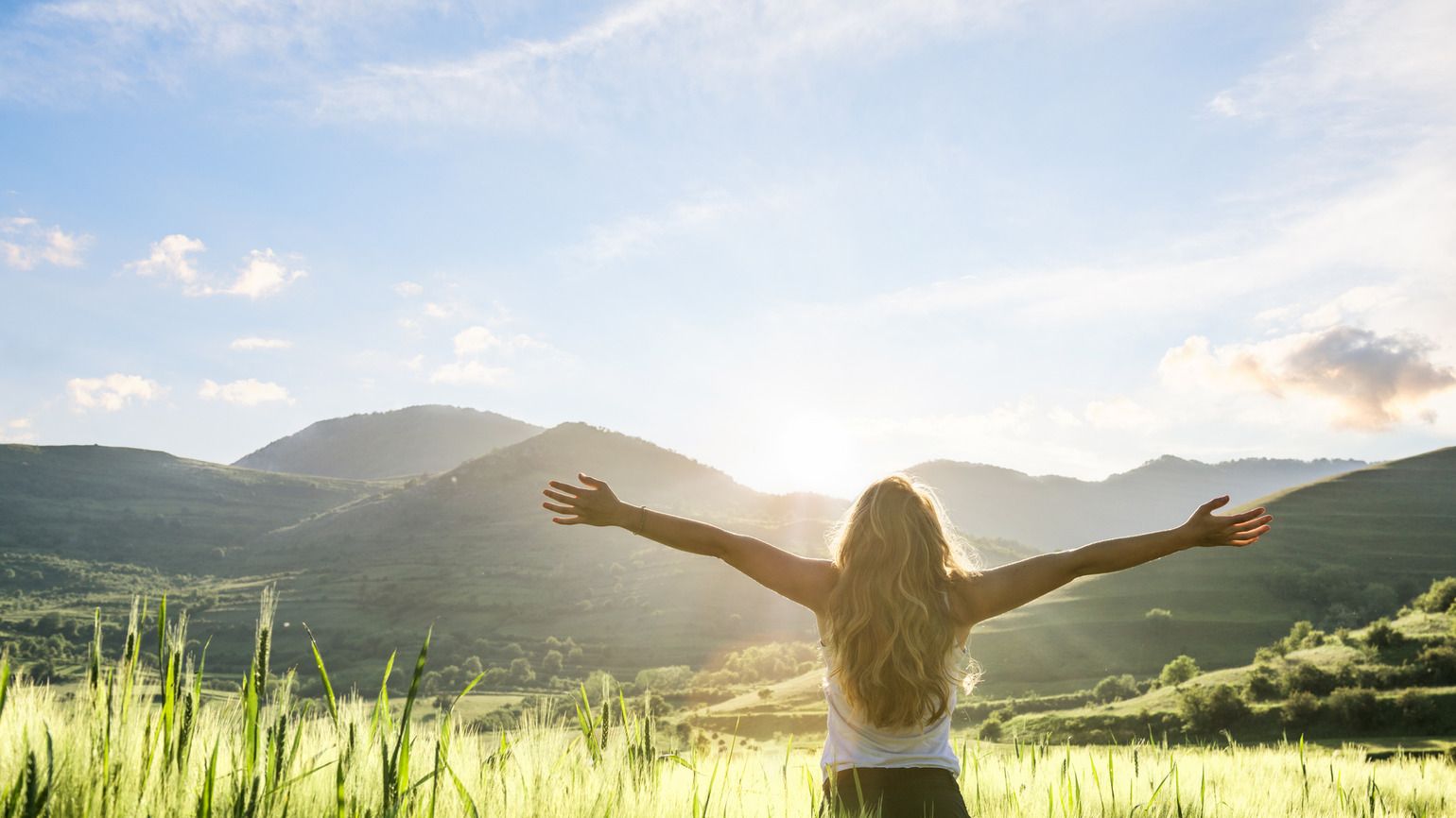 Woman in nature with hands outstretched having a beautiful fresh morning; Getty Images