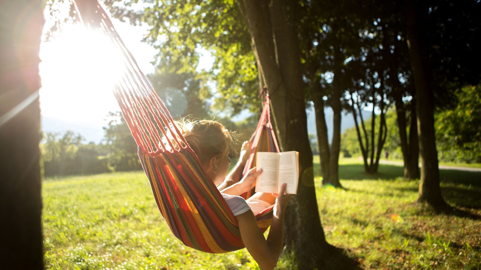 Woman on hammock at sunset reading book (Getty Images)