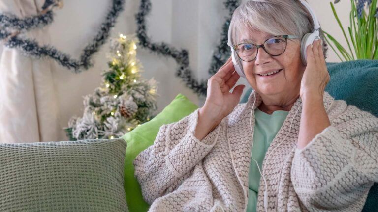 A senior woman listening to music during the holidays; Getty Images