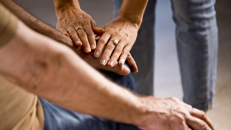 Woman caretaker holding seniors hands