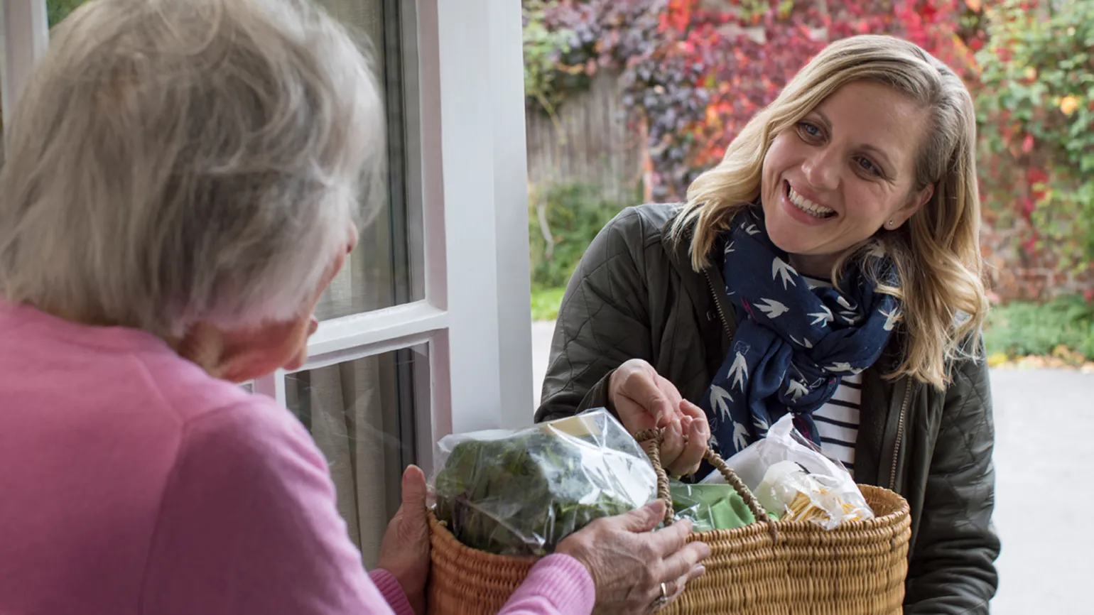 Woman giving neighbor groceries