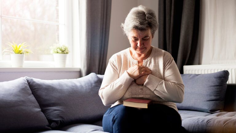 Senior woman praying at home