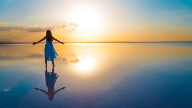 A woman greets the sunrise at the beach