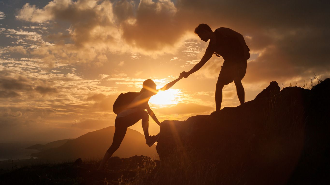 A hiker helping their friend at sunset for God's hands