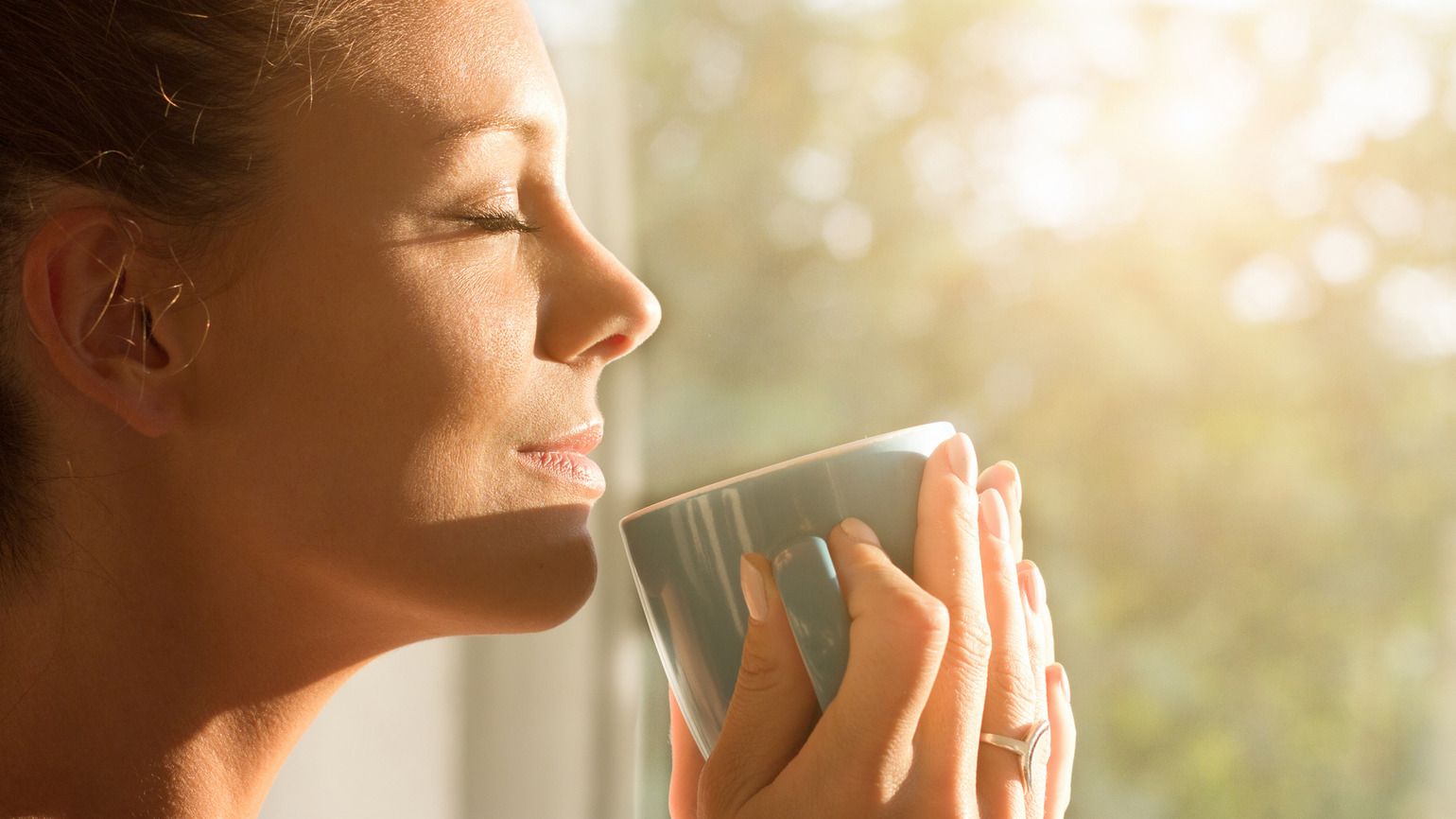 A woman having a cup of coffee in the morning sunlight thinking of God's hands