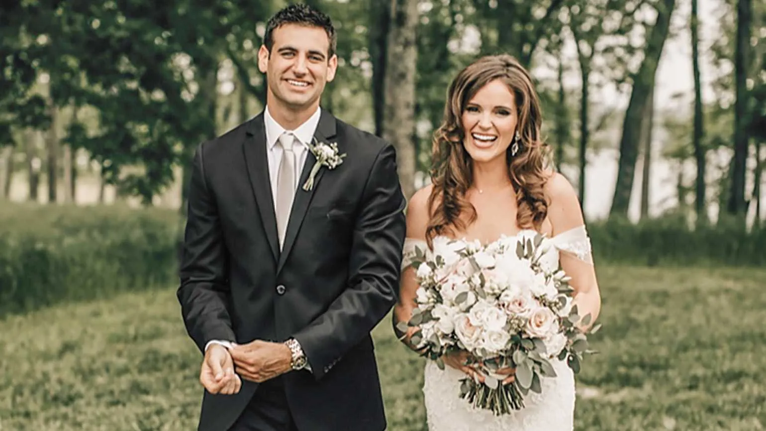 A bride and groom smiling at the camera telling their true love story