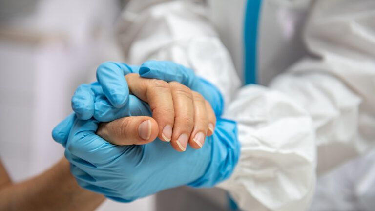 Healthcare worker holding a patients hand
