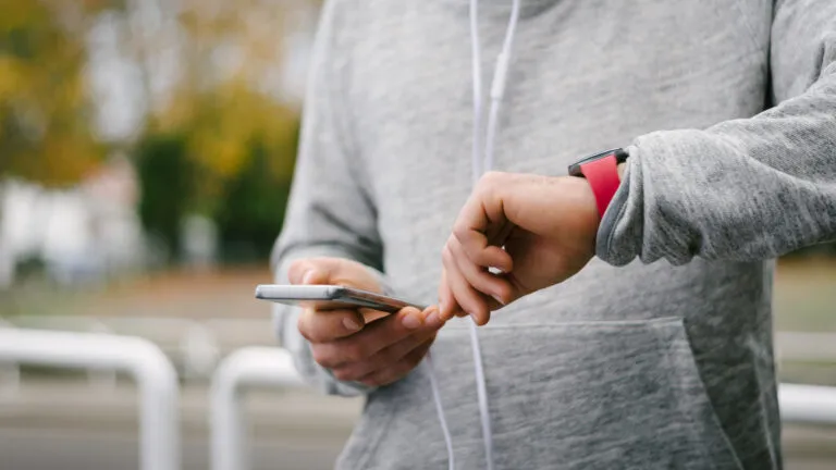 Man looking at his watch so he stops doomscrolling on his phone