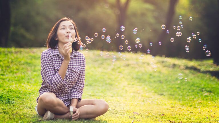 Woman blowing bubbles in a field after reading Easter Bible verses