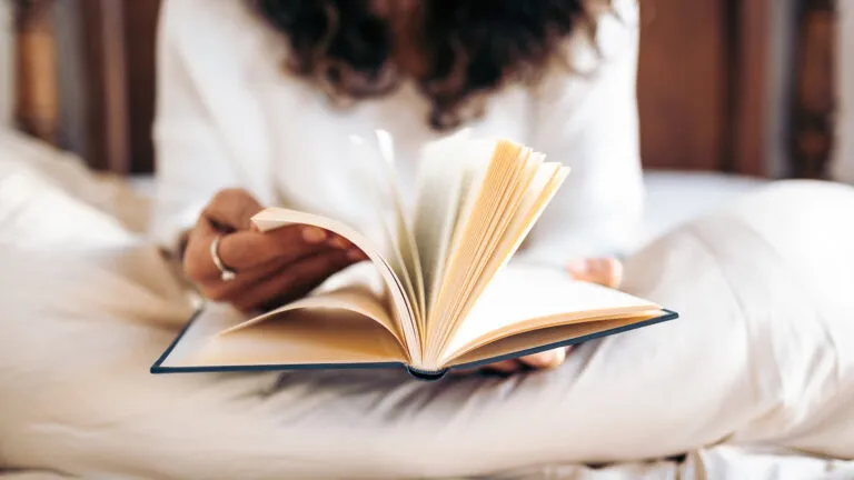 Woman reading a book before bed to avoid doomscrolling