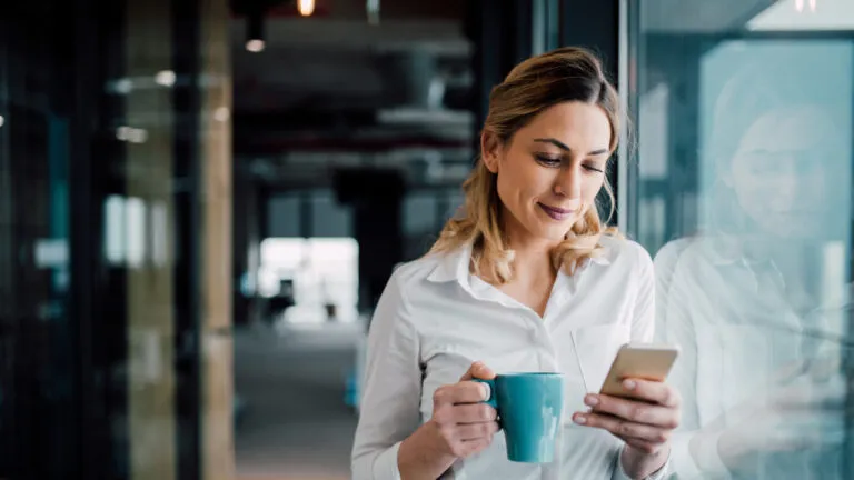 business woman doomscrolling on her phone while she drinks coffee