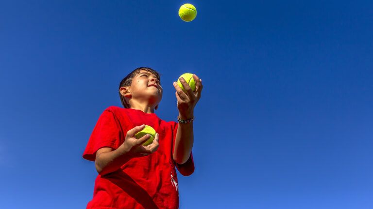A boy juggles tennis balls