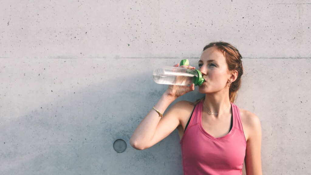 A woman drinking water after a workout thinking about Bible verses for walking and running