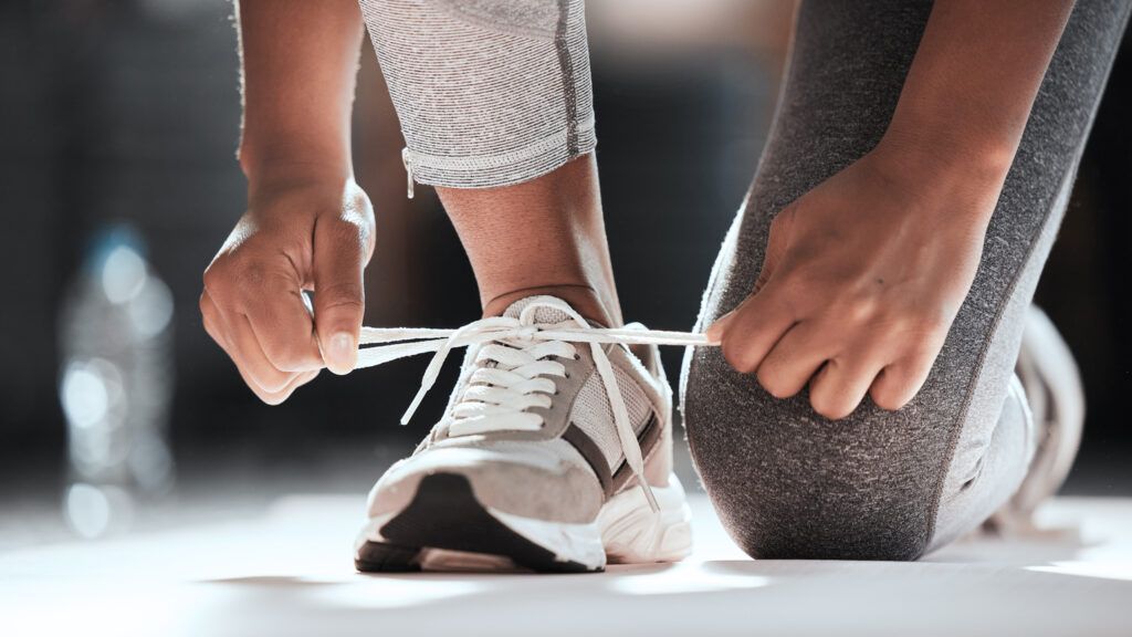 A woman trying her shoelaces for a workout with Bible verses for walking and running
