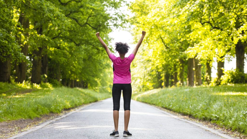 A woman with her arm raised standing in the road using Bible verses for walking and running