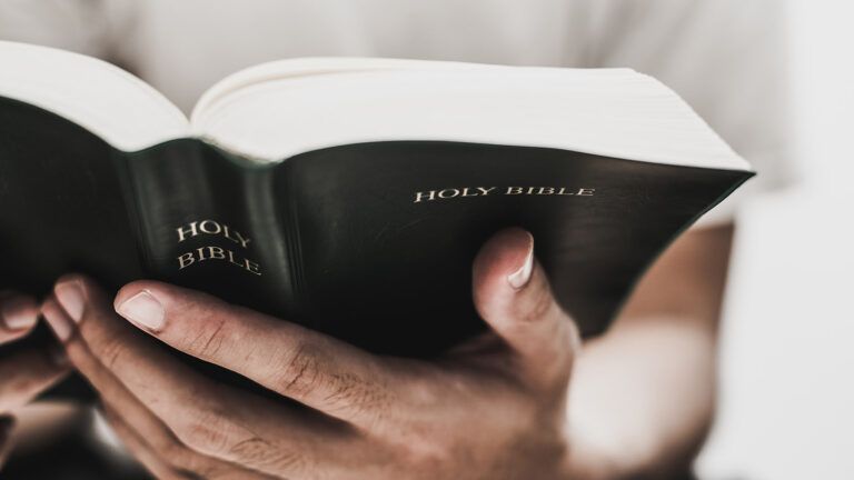 A man's hands grasp an open Bible